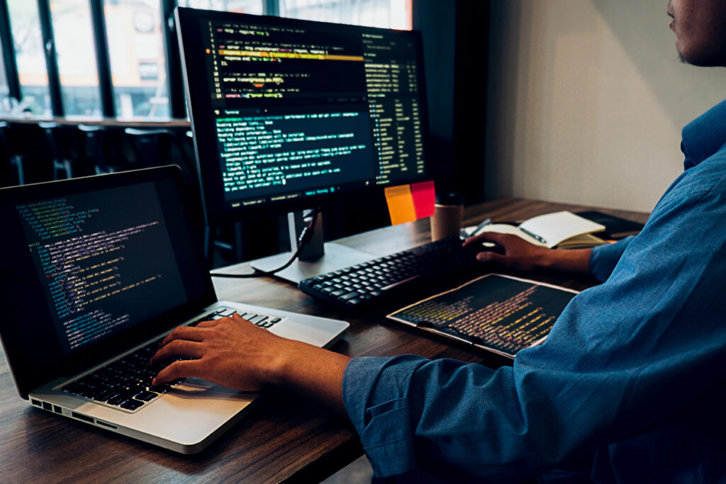 Software developer working on three screens to create code.