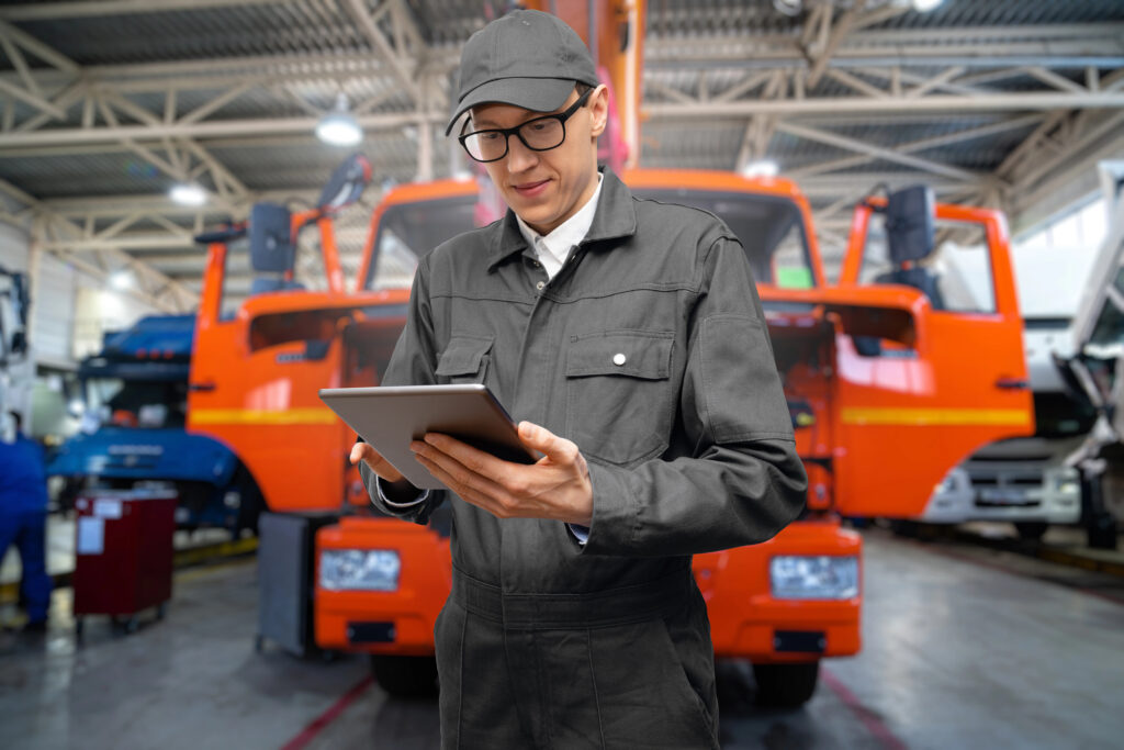 Technician using a tablet in a commercial truck service bay.